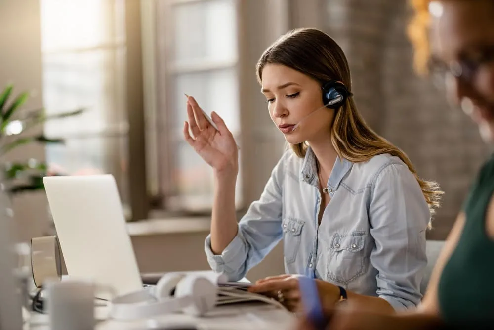 young-businesswoman-wearing-headset-and-communicating-with-client-while-going-through-paperwork-in-the-office (1)