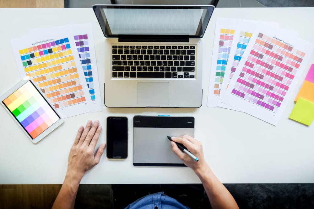 top-view-of-young-graphic-designer-working-on-desktop-computer-and-using-some-color-swatches-top-view (1) (1)