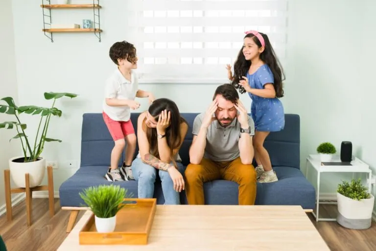stressed-upset-young-parents-feeling-tired-while-their-misbehaved-children-and-jump-on-the-couch-around-them (1)