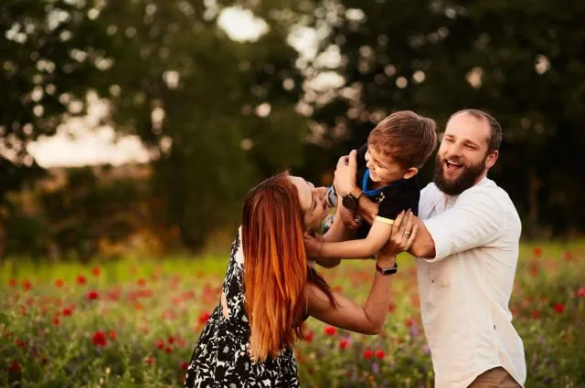 mom-and-dad-hold-their-little-son-on-the-arms-standing-on-the-green-field-with-poppies (1) (1)