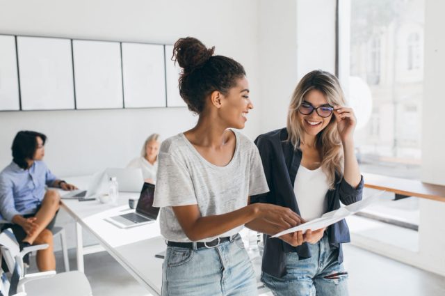 young-female-executive-explaines-new-strategy-to-blonde-employee-in-glasses-and-smiling-indoor-portrait-of-multicultural-collective-working-on-project-in-office-and-using-laptop (1)